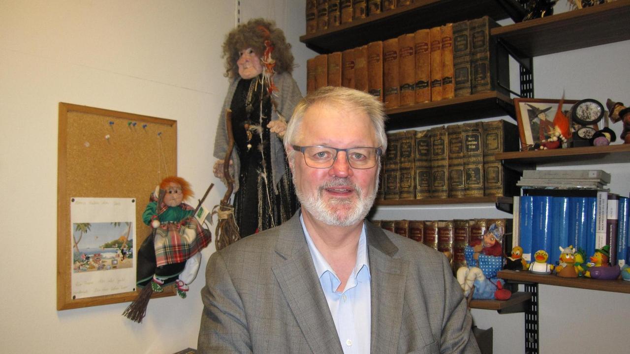 Historiker Thomas Becker vor Hexenfiguren in seinem Büro