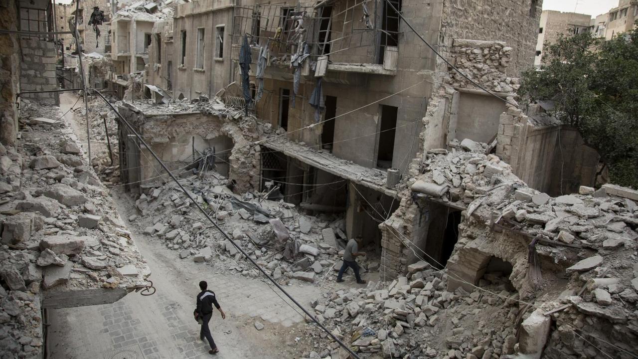 Ein Mann läuft durch eine Straße mit völlig zerstörten Häusern in Aleppo Ein Mann läuft durch eine Straße mit völlig zerstörten Häusern in Aleppo