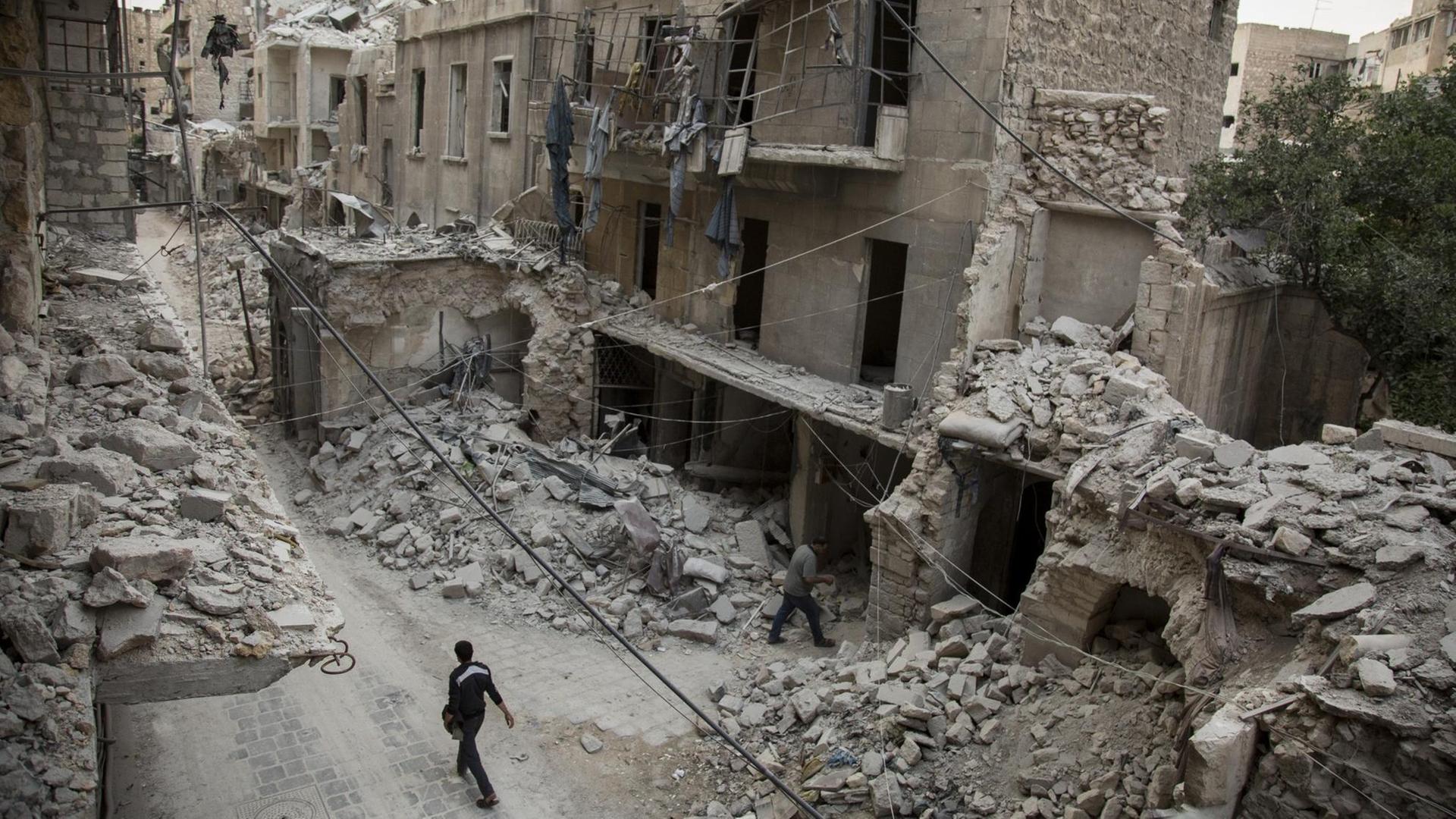 Ein Mann läuft durch eine Straße mit völlig zerstörten Häusern in Aleppo Ein Mann läuft durch eine Straße mit völlig zerstörten Häusern in Aleppo