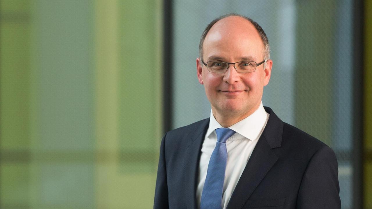 Stefan Gerwens steht im Anzug vor einem grafischen Hintergrund und blickt in die Kamera. Stefan Gerwens steht im Anzug vor einem grafischen Hintergrund und blickt in die Kamera.