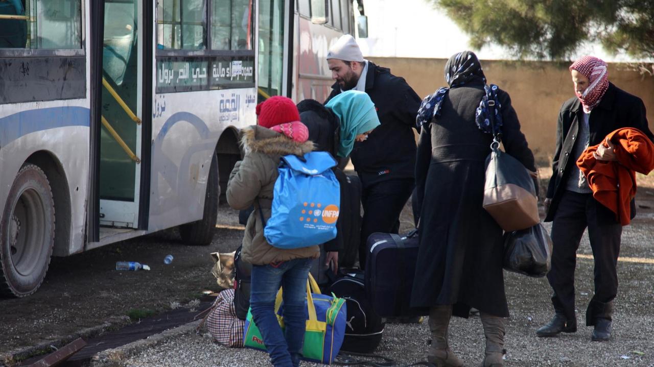 Eine syrische Familie mit Koffern und Taschen vor einem Bus, Eine syrische Familie mit Koffern und Taschen vor einem Bus,