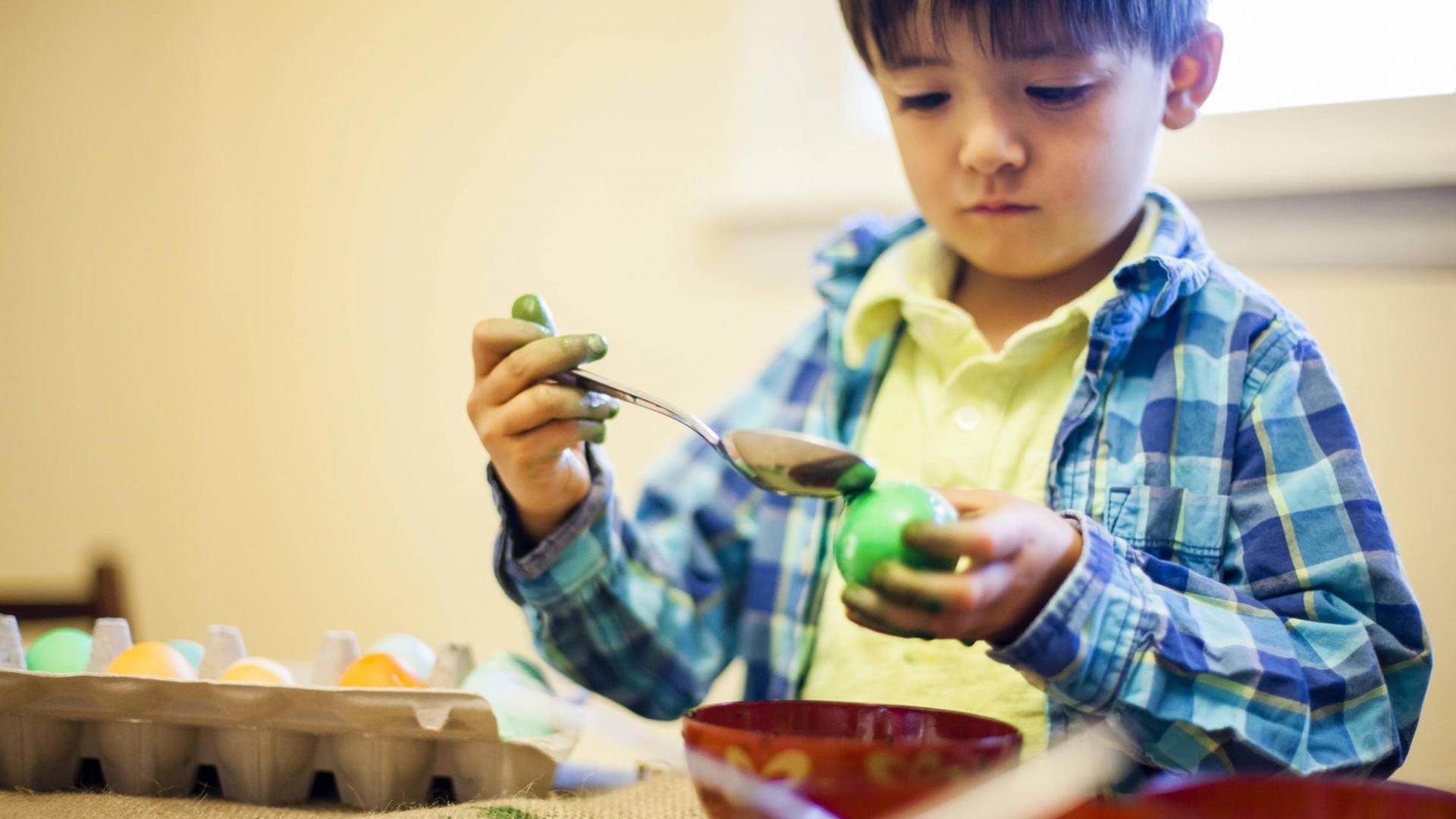 Ein vierjähriger Junge färbt ein Osterei (Symbolfoto).