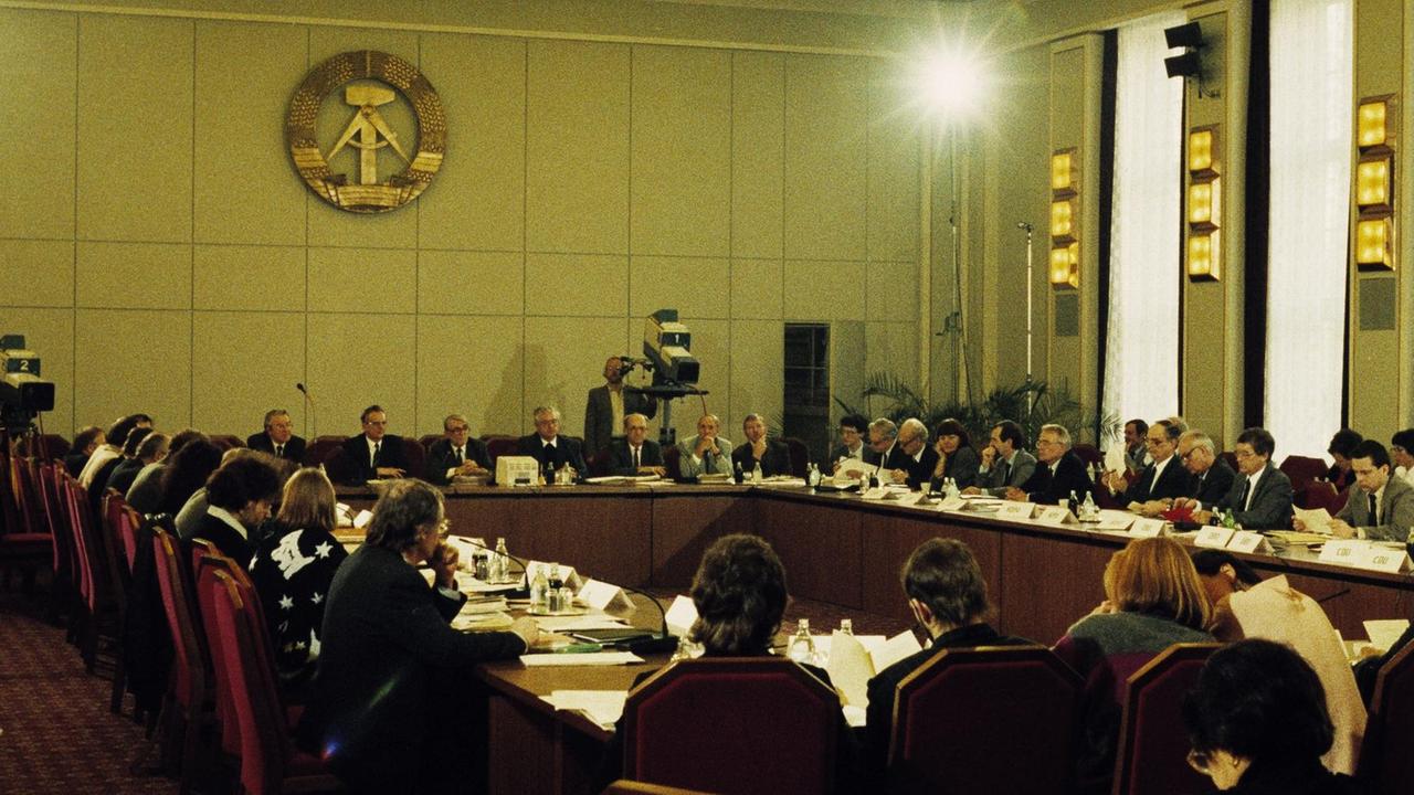 Ost-Berlin, 19. Februar 1990. 13. Sitzung des sogenannten Runden Tisches. Diskussion zwischen Vertretern der SPD, des Neuen Forums, der CDU, der Grünen Partei, des Demokrat. Aufbruchs, des FDGB, der Vereinigten Linken u. a. mit Vertretern der Regierung der DDR. Als Moderatoren fungieren Vertreter der Kirchen. Ost-Berlin, 19. Februar 1990. 13. Sitzung des sogenannten Runden Tisches. Diskussion zwischen Vertretern der SPD, des Neuen Forums, der CDU, der Grünen Partei, des Demokrat. Aufbruchs, des FDGB, der Vereinigten Linken u. a. mit Vertretern der Regierung der DDR. Als Moderatoren fungieren Vertreter der Kirchen.