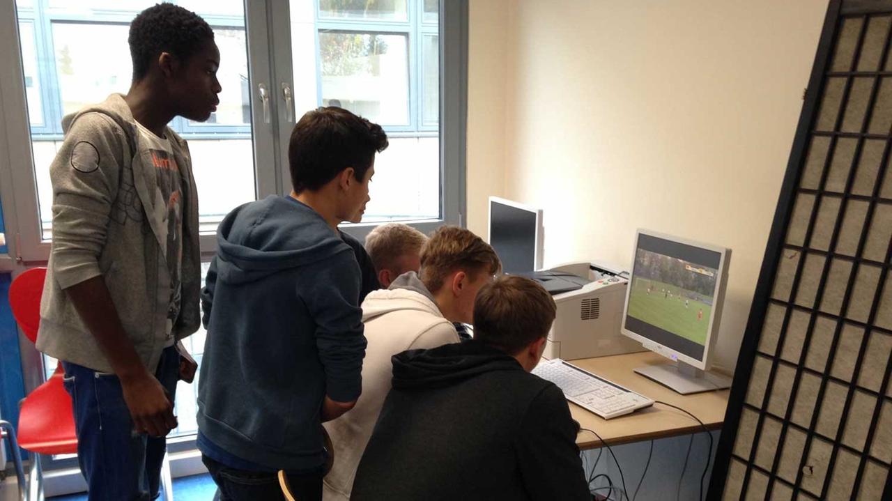 Eine Gruppe Schüler hat sich um einen PC in der Geißbockakademie versammelt und schaut sich ein Spiel vom vergangenen Wochenende an. Eine Gruppe Schüler hat sich um einen PC in der Geißbockakademie versammelt und schaut sich ein Spiel vom vergangenen Wochenende an.