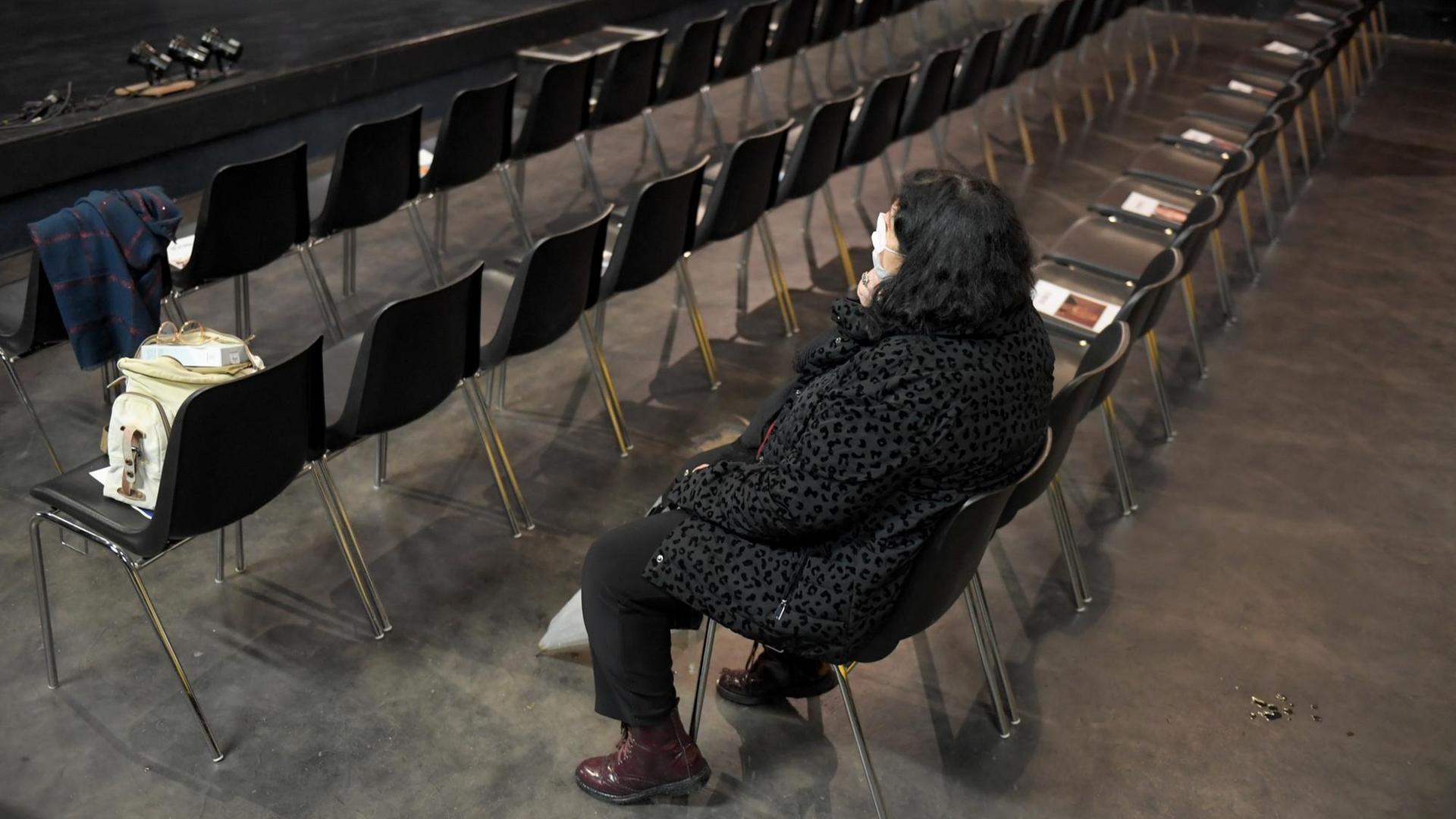Eine Frau sitzt im Zuschauerraum eines leeren Theaters. Eine Frau sitzt im Zuschauerraum eines leeren Theaters.