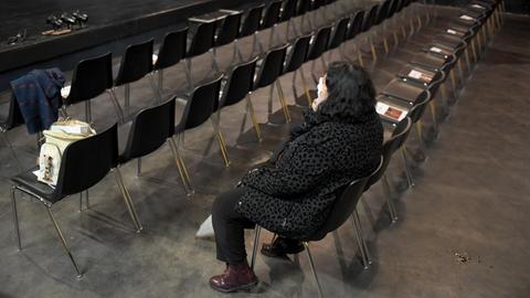 Eine Frau sitzt im Zuschauerraum eines leeren Theaters.