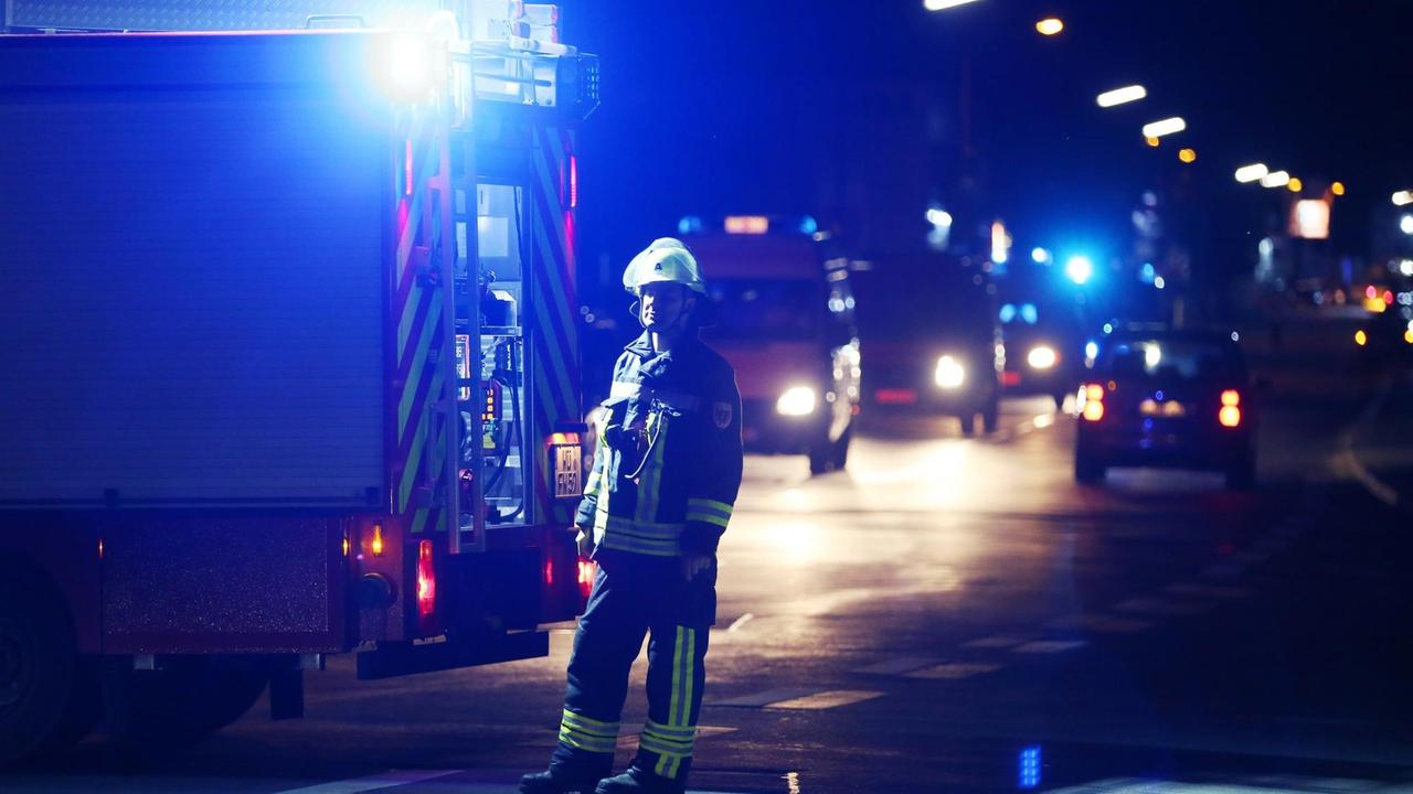 Ein Feuerwehrmann steht am in Würzburg an einer Straßenabsperrung. Im Hintergrund sind Einsatzfahrzeuge und Blaulichter zu sehen. Ein Feuerwehrmann steht am in Würzburg an einer Straßenabsperrung. Im Hintergrund sind Einsatzfahrzeuge und Blaulichter zu sehen.