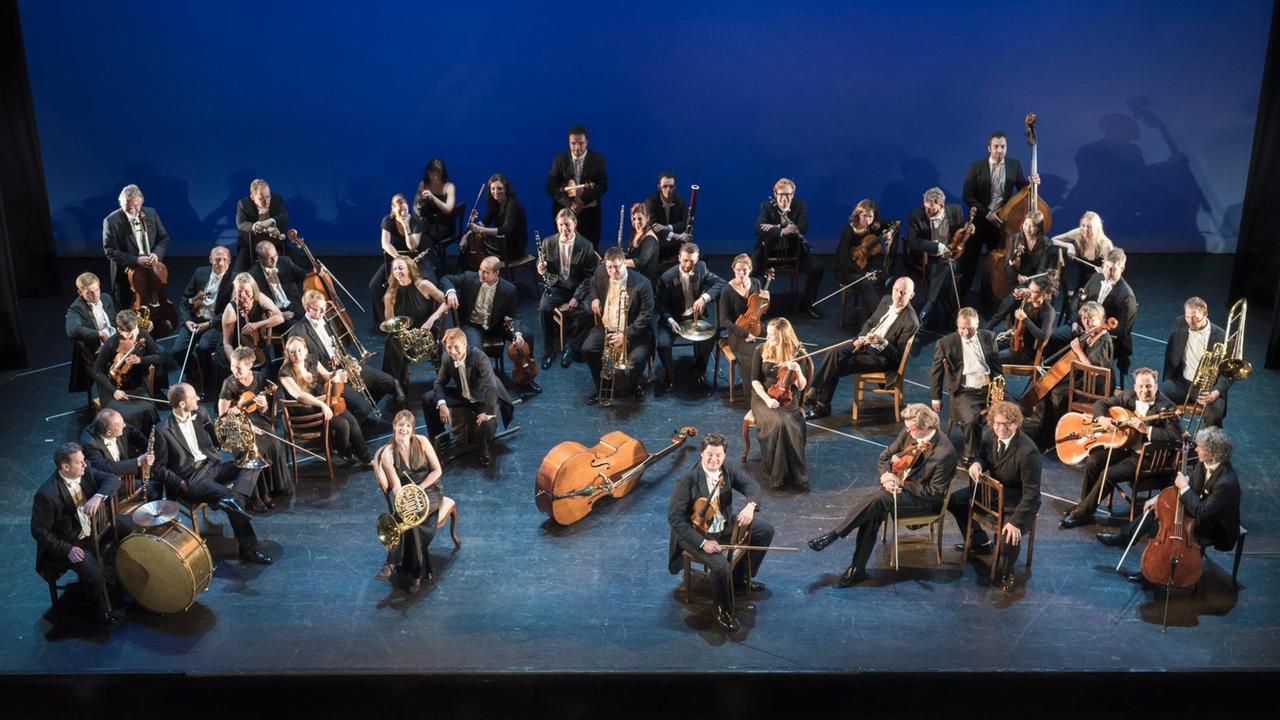 Ein Kontrabass liegt auf der Bühne, darum gruppieren sich die Musiker der Cappella. Ein Kontrabass liegt auf der Bühne, darum gruppieren sich die Musiker der Cappella.