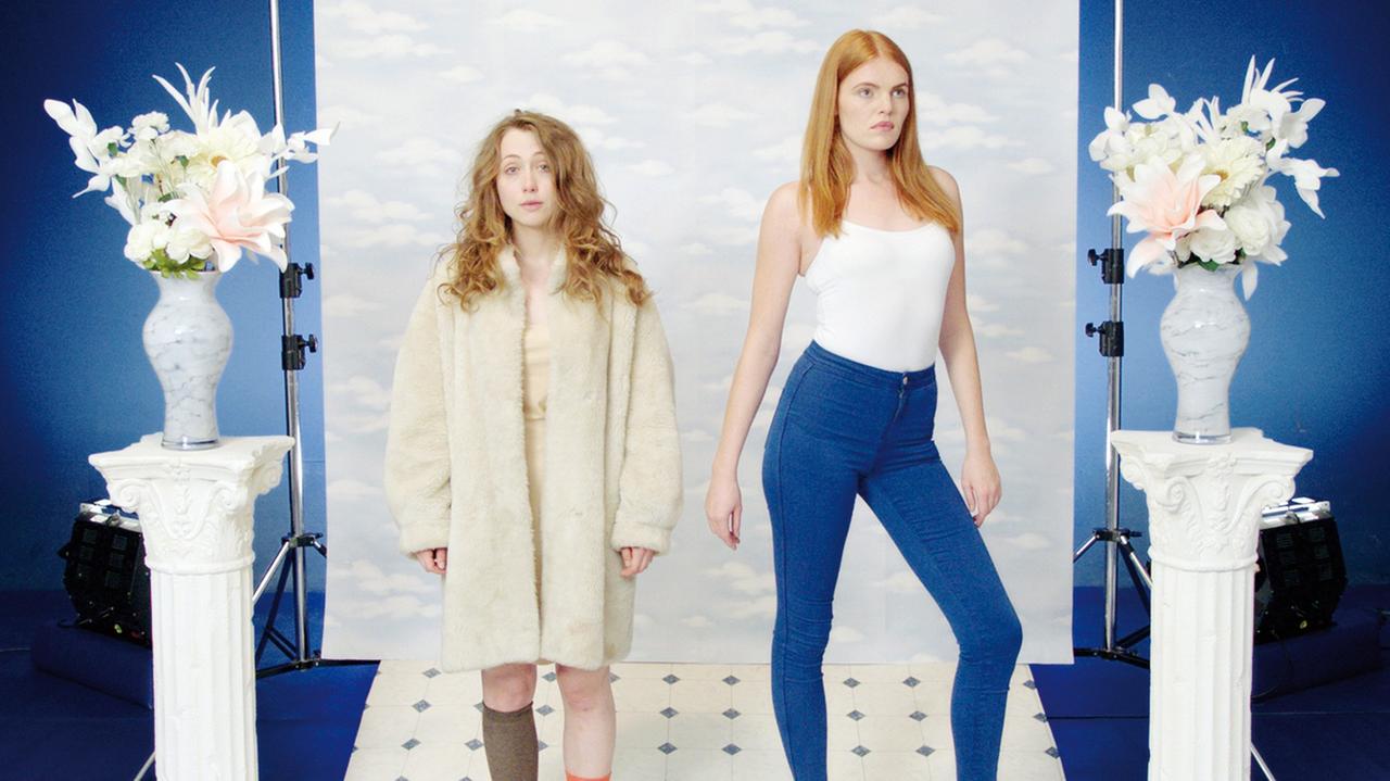 Das melancholische Mädchen steht an einem Filmset neben einem Modell, welches in die Ferne starrt. Zitat aus der Filmszene: "Feminismus zu verkaufen!". Das melancholische Mädchen steht an einem Filmset neben einem Modell, welches in die Ferne starrt. Zitat aus der Filmszene: "Feminismus zu verkaufen!".