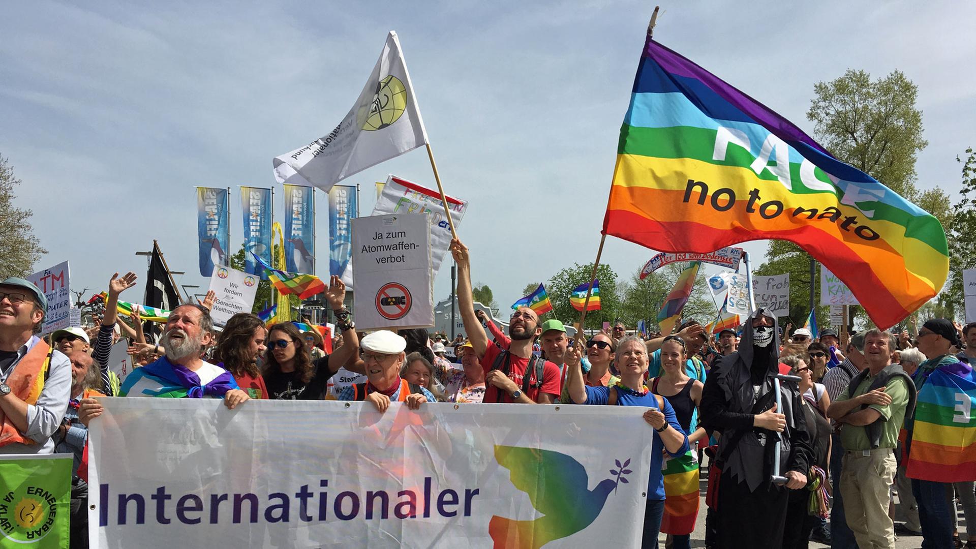 Hinter einem Transparent mit einer weißen Friedenstaube haben sich buntgekleidete Friedensaktivisten versammelt. Hinter einem Transparent mit einer weißen Friedenstaube haben sich buntgekleidete Friedensaktivisten versammelt.