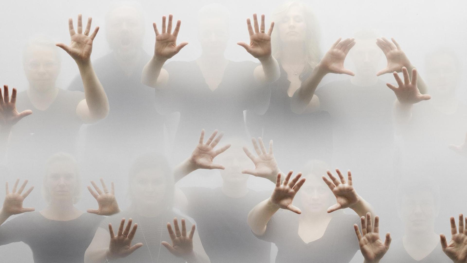 Die Chormitglieder stehen mitten im Nebel, vor allem ihre ausgespreizten Hände treten hervor. Die Chormitglieder stehen mitten im Nebel, vor allem ihre ausgespreizten Hände treten hervor.