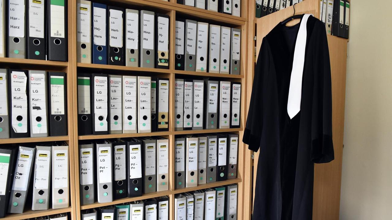 Eine Richterrobe hängt am 06.08.2014 in Berlin in einem Raum eines Gerichts auf einem Bügel an einem Schrank neben vielen Aktenordnern.