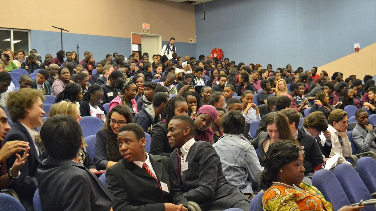 Ein Hörsaal der African Leadership Academy mit zahlreichen Studierende auf blauen gepolsterten Sitzen . Ein Hörsaal der African Leadership Academy mit zahlreichen Studierende auf blauen gepolsterten Sitzen .