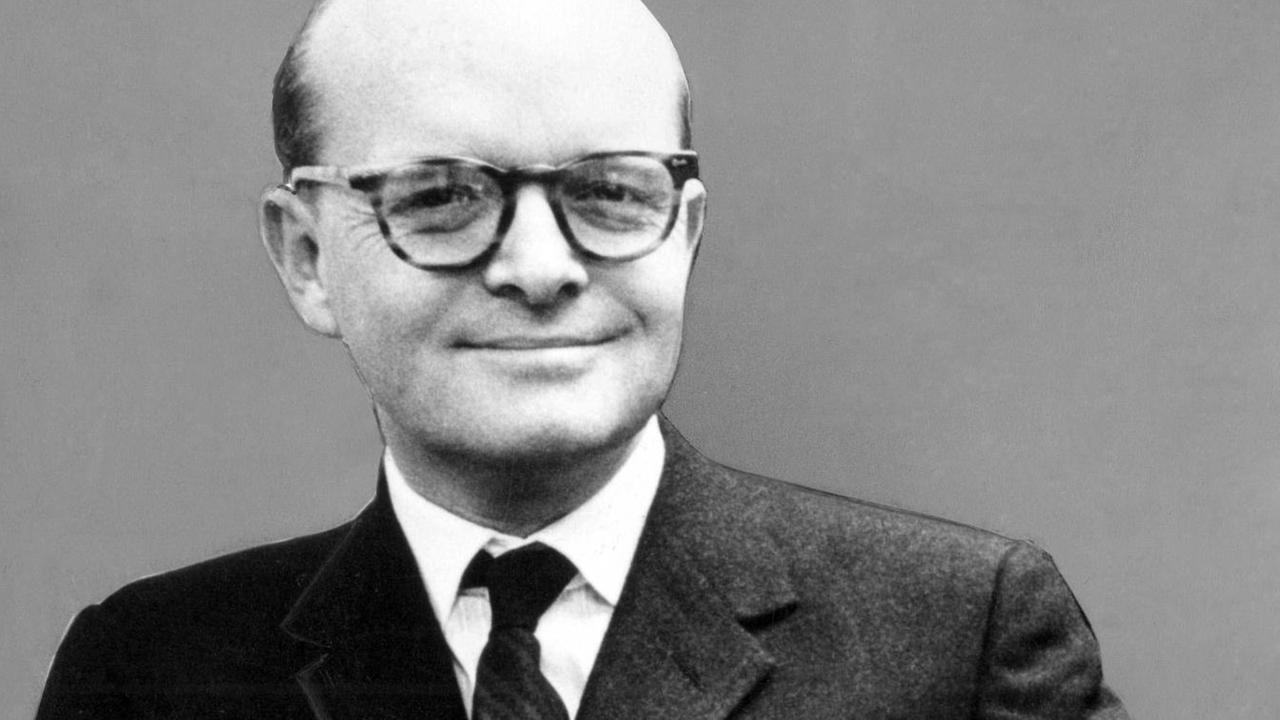 Truman Capote im Anzug: Er grinst in die Kamera und trägt Bücher unter dem Arm Truman Capote im Anzug: Er grinst in die Kamera und trägt Bücher unter dem Arm