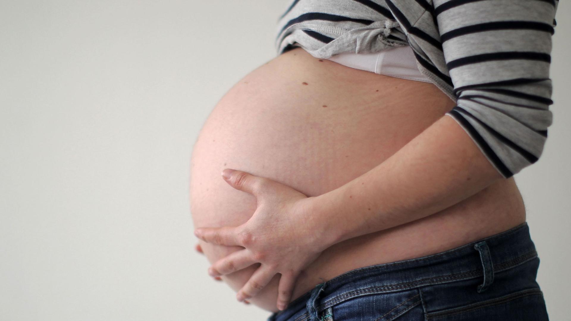 Eine schwangere Frau hält ihren Bauch. Eine schwangere Frau hält ihren Bauch.