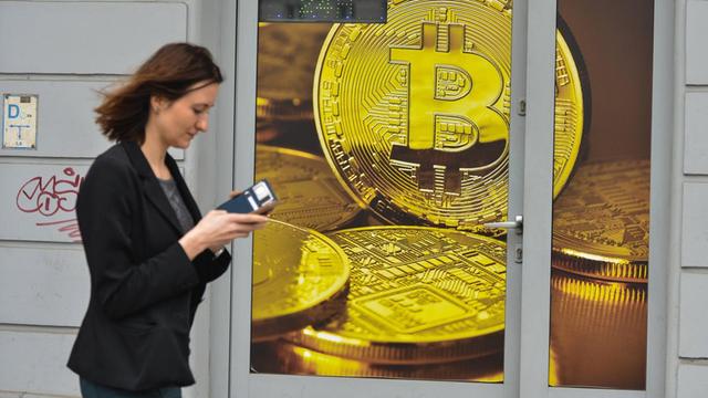 Eine Frau geht an einem Wechselshop für Bitcoins vorbei.
