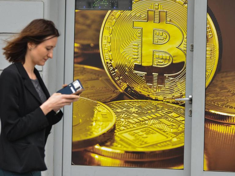Eine Frau geht an einem Wechselshop für Bitcoins vorbei.