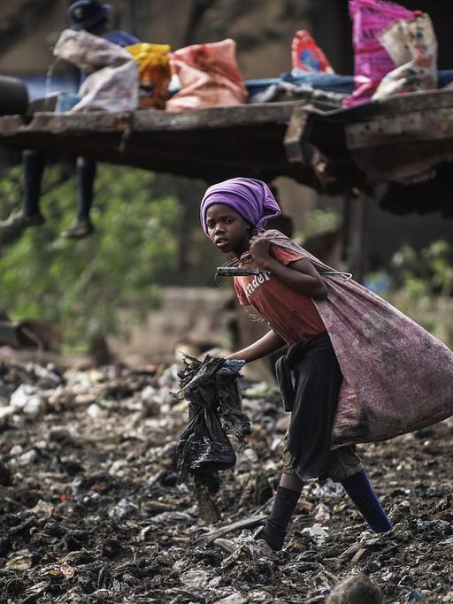 Ein Mädchen läuft in Maputo in Mosambik über eine Müllhalde und sammelt noch verwertbaren Abfall.