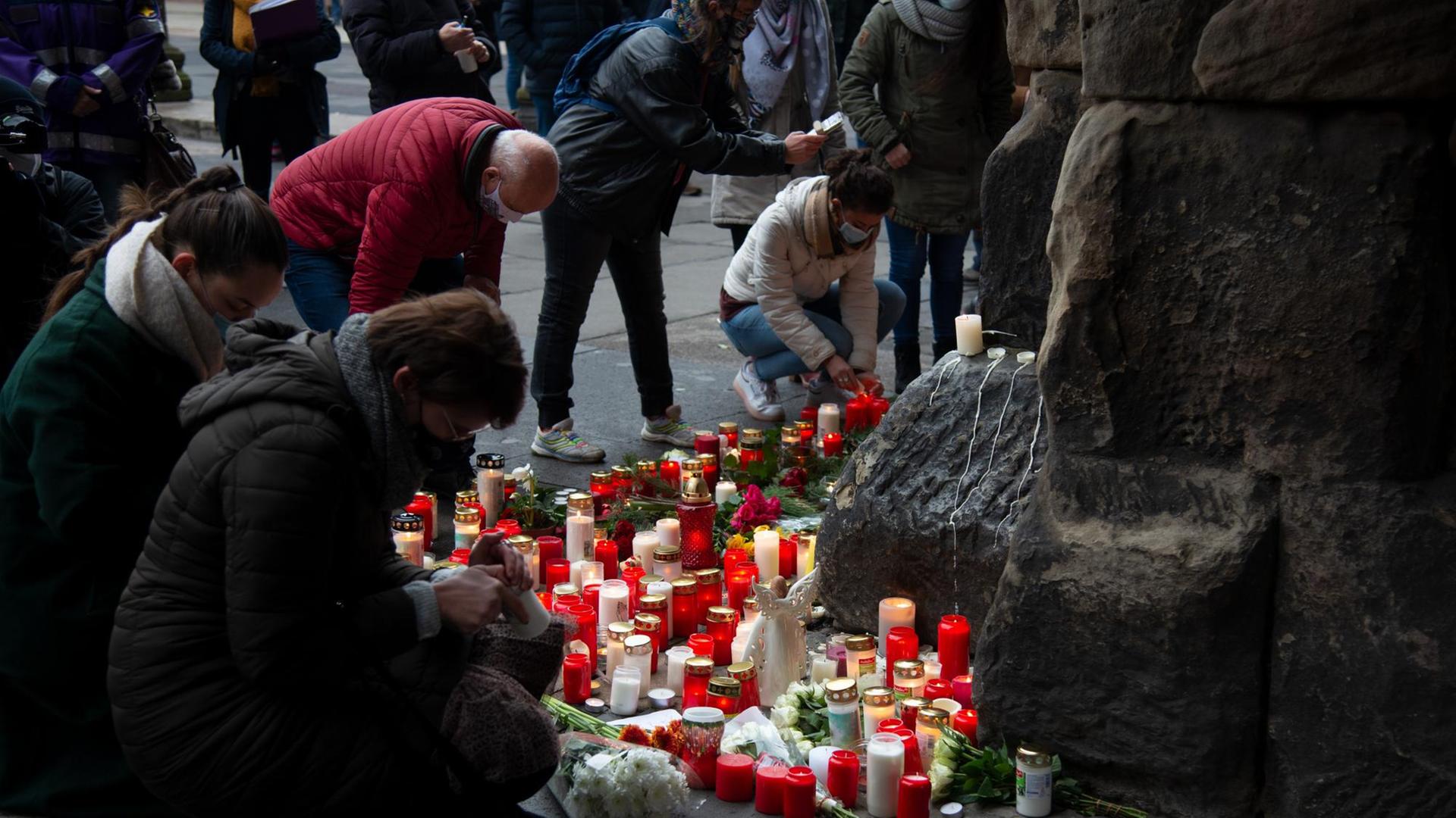 Das Foto zeigt Menschen, die Kerzen und Blumen auf die Erde legen. Das Foto zeigt Menschen, die Kerzen und Blumen auf die Erde legen.