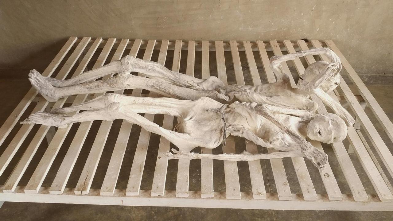 Mumifizierte Leichen in der Völkermordgedenkstätte Murambi in Ruanda. Wie Skelette liegen sie auf Holzbrettern in einem unverputzten Raum.