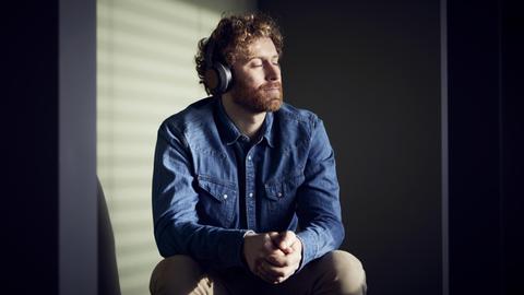 Ein Mann mit geschlossenen Augen hört über Kopfhörer Musik