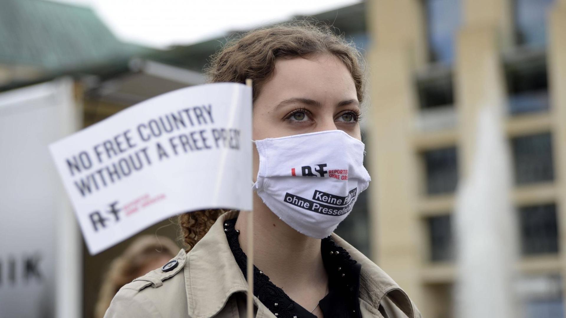Eine junge Frau trägt Berlin bei einer Aktion von Reporter ohne Grenzen einen Mundschutz auf dem "Keine Freiheit ohne Pressefreiheit" gedruckt steht. Eine junge Frau trägt Berlin bei einer Aktion von Reporter ohne Grenzen einen Mundschutz auf dem "Keine Freiheit ohne Pressefreiheit" gedruckt steht.