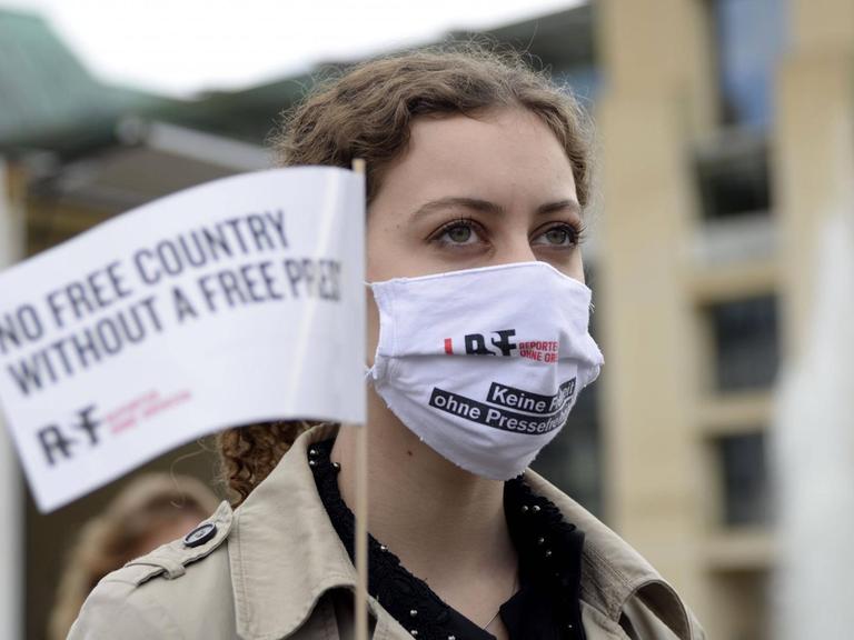 Eine junge Frau trägt Berlin bei einer Aktion von Reporter ohne Grenzen einen Mundschutz auf dem "Keine Freiheit ohne Pressefreiheit" gedruckt steht.