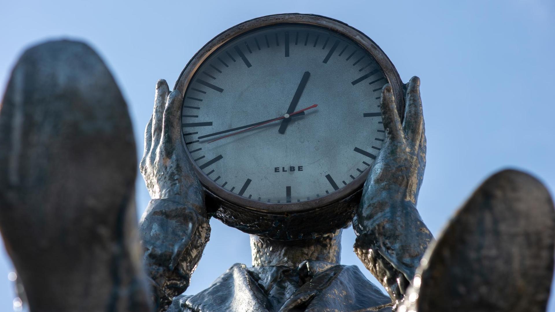 Magdeburg, Sachsen-Anhalt: Die Skulptur "Zeitzähler" von Gloria Friedmann mit einer Uhr vor dem Gesicht. Magdeburg, Sachsen-Anhalt: Die Skulptur "Zeitzähler" von Gloria Friedmann mit einer Uhr vor dem Gesicht.