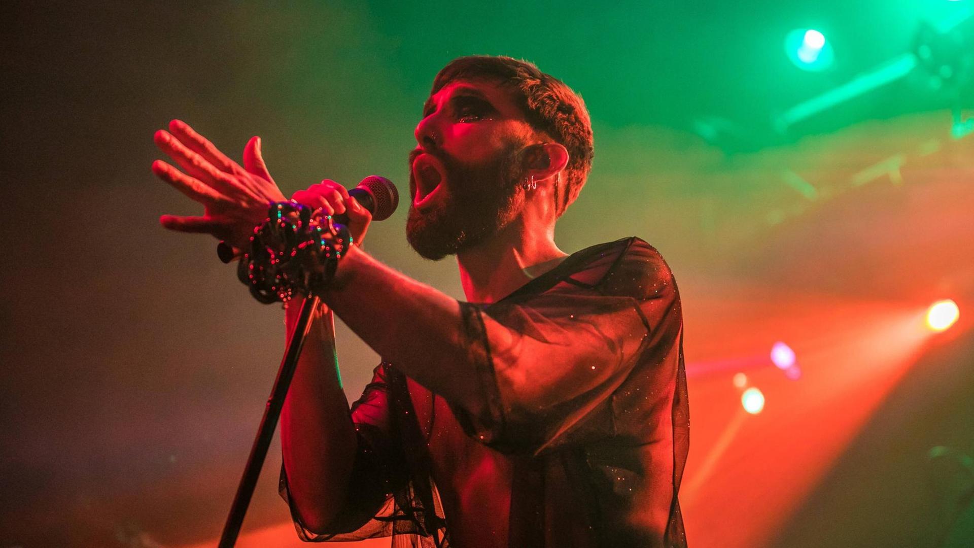 Thomas Neuwirth bei einem Konzert auf der Bühne. Kurze Haare, Bart, durchsichtiges Oberteil. Thomas Neuwirth bei einem Konzert auf der Bühne. Kurze Haare, Bart, durchsichtiges Oberteil.
