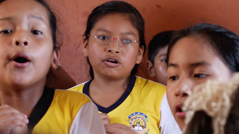 Ein Mädchen mit einer Brille singt in einer Gruppe von Schülern