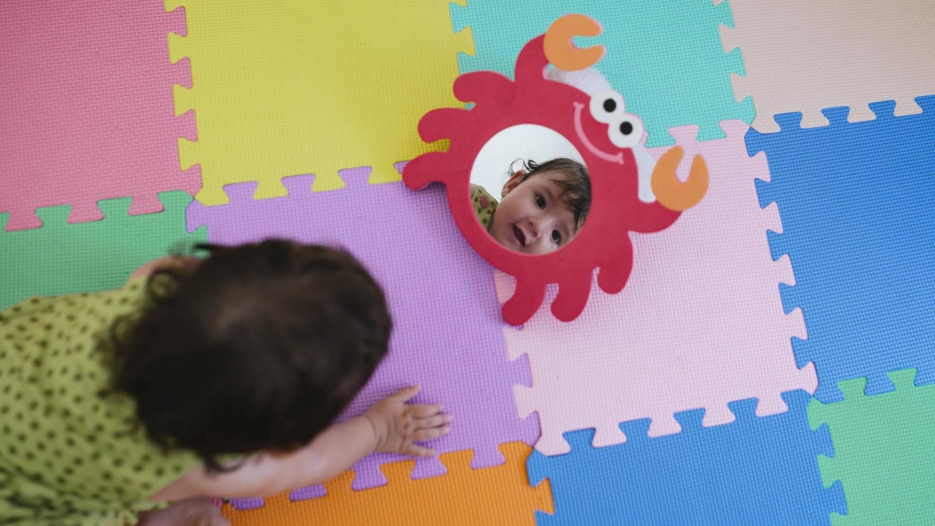 Ein Baby schaut sich im Spielzeugspiegel an Ein Baby schaut sich im Spielzeugspiegel an