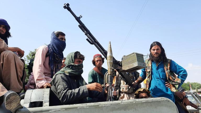 Schwer bewaffnete Taliban-Kämpfer fahren in einem Fahrzeug durch Mehtarlam, die Hauptstadt der afghanischen Provinz Laghman.