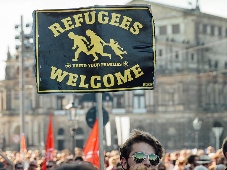 Teilnehmer einer Demonstration stehen Ende August 2015 mit einem Schild mit der Aufschrift "Refugees welcome" in der Dresdner Innenstadt.