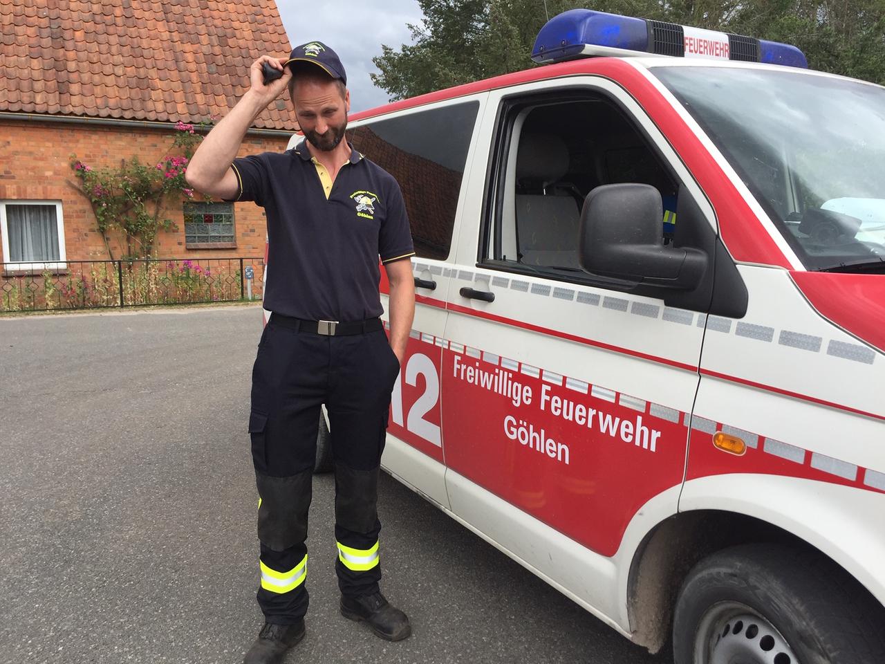 Ein Feuerwehrmann steht mit gerunzelter Stirn vor seinem Einsatzfahrzeug Ein Feuerwehrmann steht mit gerunzelter Stirn vor seinem Einsatzfahrzeug