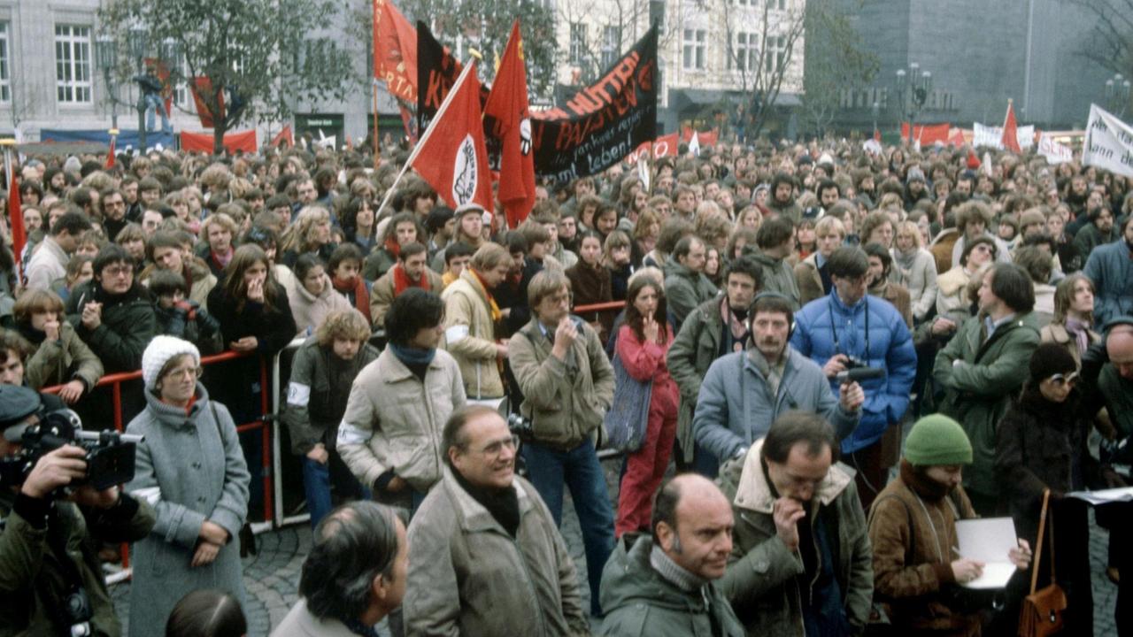 Auf dem Bonner Münsterplatz demonstrieren am 08.11.1980 Bürger hinter einer Absperrung gegen das öffentliche Rekrutengelöbnis. Davor Pressevertreter. | Verwendung weltweit