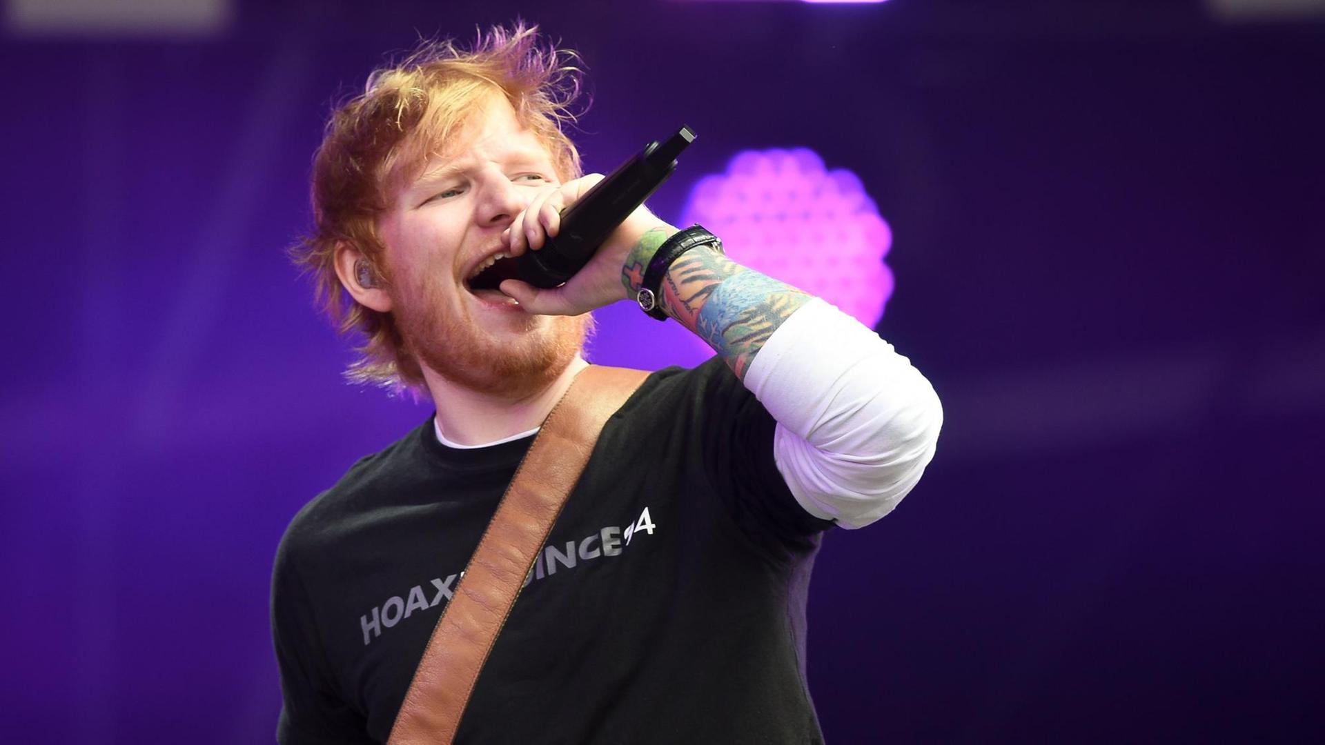Der Künstler Ed Sheeran hält bei einem Konzert ein Mikrofon in der Hand und singt. Der Künstler Ed Sheeran hält bei einem Konzert ein Mikrofon in der Hand und singt.