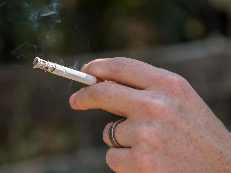 Eine Frau raucht am in einem Wald bei Hamburg eine Zigarette