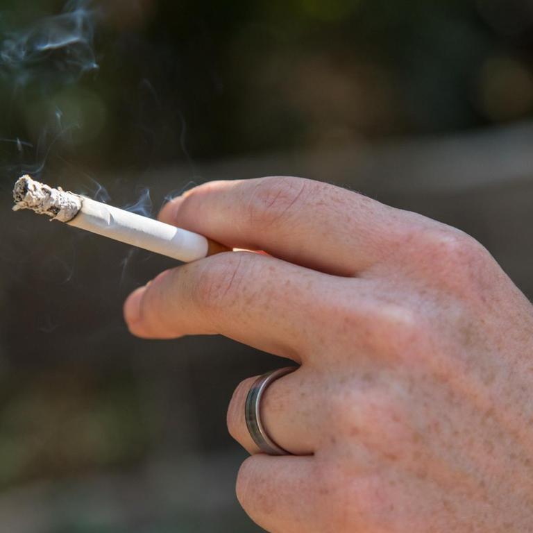Eine Frau raucht am in einem Wald bei Hamburg eine Zigarette