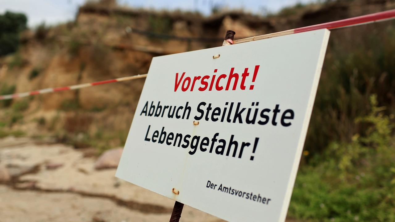 Ein Warnschild weist am 22.08.2013 auf die Abbruchgefahr an der Steilküste am Strand von Klein Zicker (Mecklenburg-Vorpommern) auf der Insel Rügen hin.