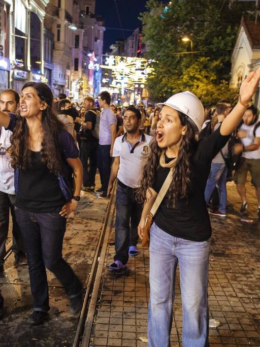 Junge Frauen mit Bauhelmen protestieren bei einer abendlichen Demonstration.