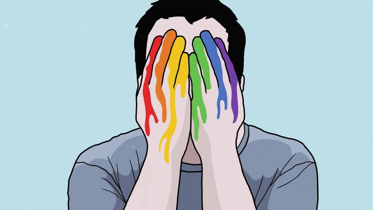 Ein Mann bedeckt sein Gesicht mit regenbogenfarbenen Händen.