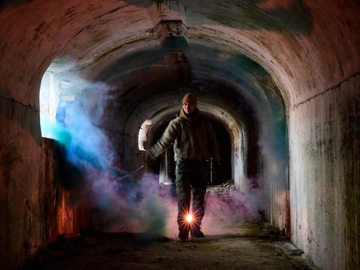 Mit einer Taschenlampe geht ein Mann durch ein verlassenes Gebäude.