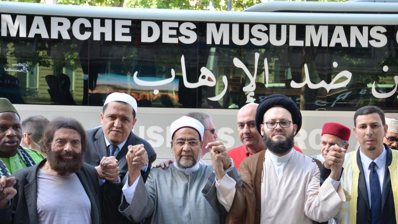 Imame beten am 08.07.2017 vor einem Bus mit der Aufschrift _Marsch der Muslime gegen den Terrorismus_ auf dem Prachtboulevard Champs-Élysées in Paris Imame beten am 08.07.2017 vor einem Bus mit der Aufschrift _Marsch der Muslime gegen den Terrorismus_ auf dem Prachtboulevard Champs-Élysées in Paris