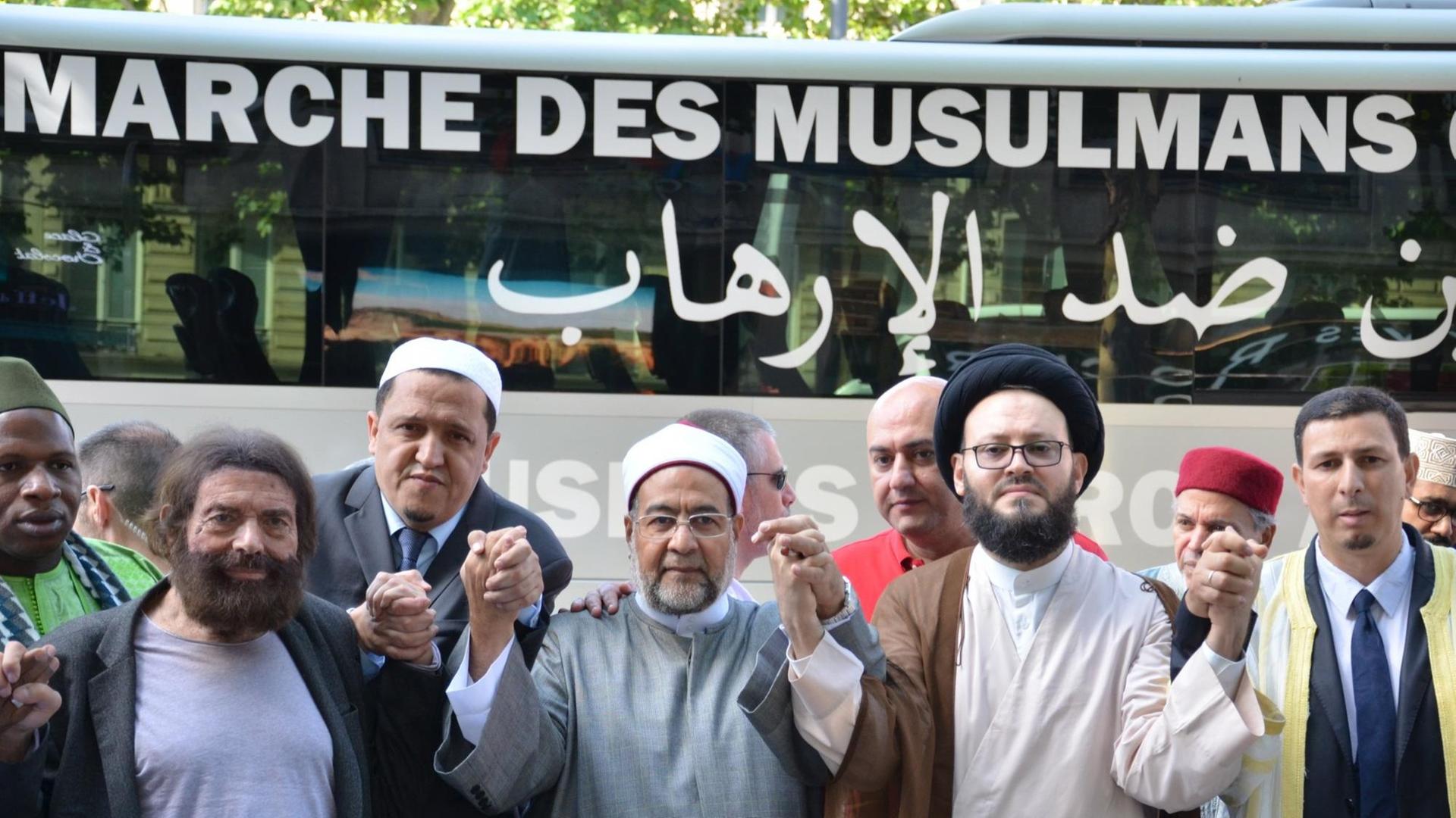 Imame beten am 08.07.2017 vor einem Bus mit der Aufschrift _Marsch der Muslime gegen den Terrorismus_ auf dem Prachtboulevard Champs-Élysées in Paris Imame beten am 08.07.2017 vor einem Bus mit der Aufschrift _Marsch der Muslime gegen den Terrorismus_ auf dem Prachtboulevard Champs-Élysées in Paris