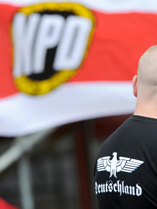 Mann mit Glatze vor NPD-Flagge