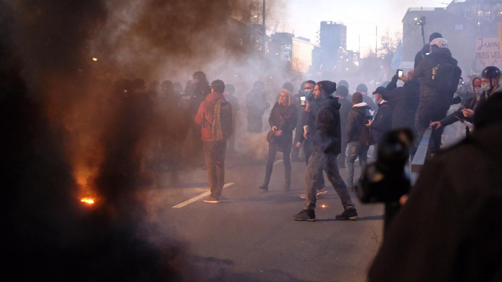 Bei einer Demonstration der Stuttgarter Initiative „Querdenken“ kommt es zu Auseinandersetzungen zwischen Teilnehmern und der Polizei. Auf der Straße stehen Demonstrierende im Rauch. Bei einer Demonstration der Stuttgarter Initiative „Querdenken“ kommt es zu Auseinandersetzungen zwischen Teilnehmern und der Polizei. Auf der Straße stehen Demonstrierende im Rauch.