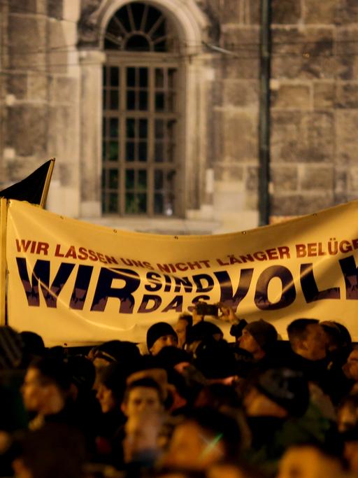Pegida-Demonstranten halten ein Tranparent hoch, auf dem "Wir sind das Volk" steht.