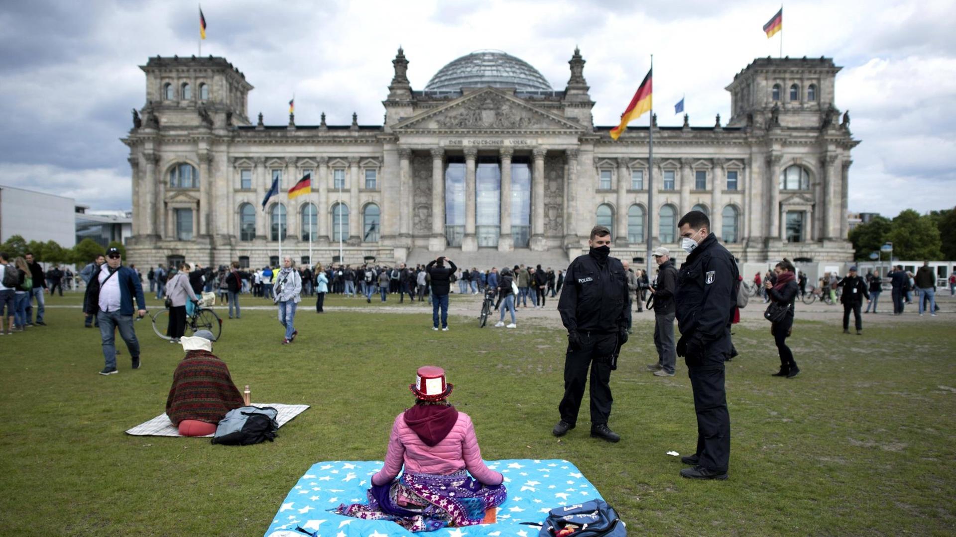 Polizisten fordern eine Frau auf den Platz zu verlassen bei einer Kundgebung gegen die Coronamassnahmen, auch Hygienedemo genannt, vor dem Deutschen Reichstag. Polizisten fordern eine Frau auf den Platz zu verlassen bei einer Kundgebung gegen die Coronamassnahmen, auch Hygienedemo genannt, vor dem Deutschen Reichstag.