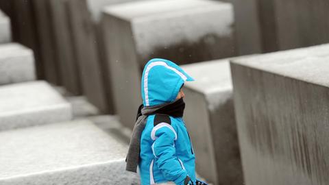 Ein kleiner Junge läuft durch das schneebedeckte Holocaust-Mahnmal in Berlin.