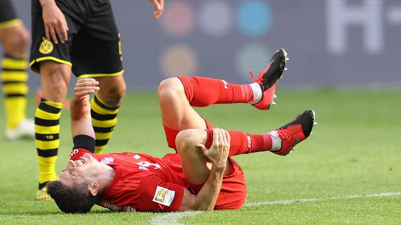 Der Fussballspieler Robert Lewandoski vom FC Bayern München liegt nach einem Foul von Łukasz Piszczek (Borussia Dortmund) am Boden. Der Fussballspieler Robert Lewandoski vom FC Bayern München liegt nach einem Foul von Łukasz Piszczek (Borussia Dortmund) am Boden.